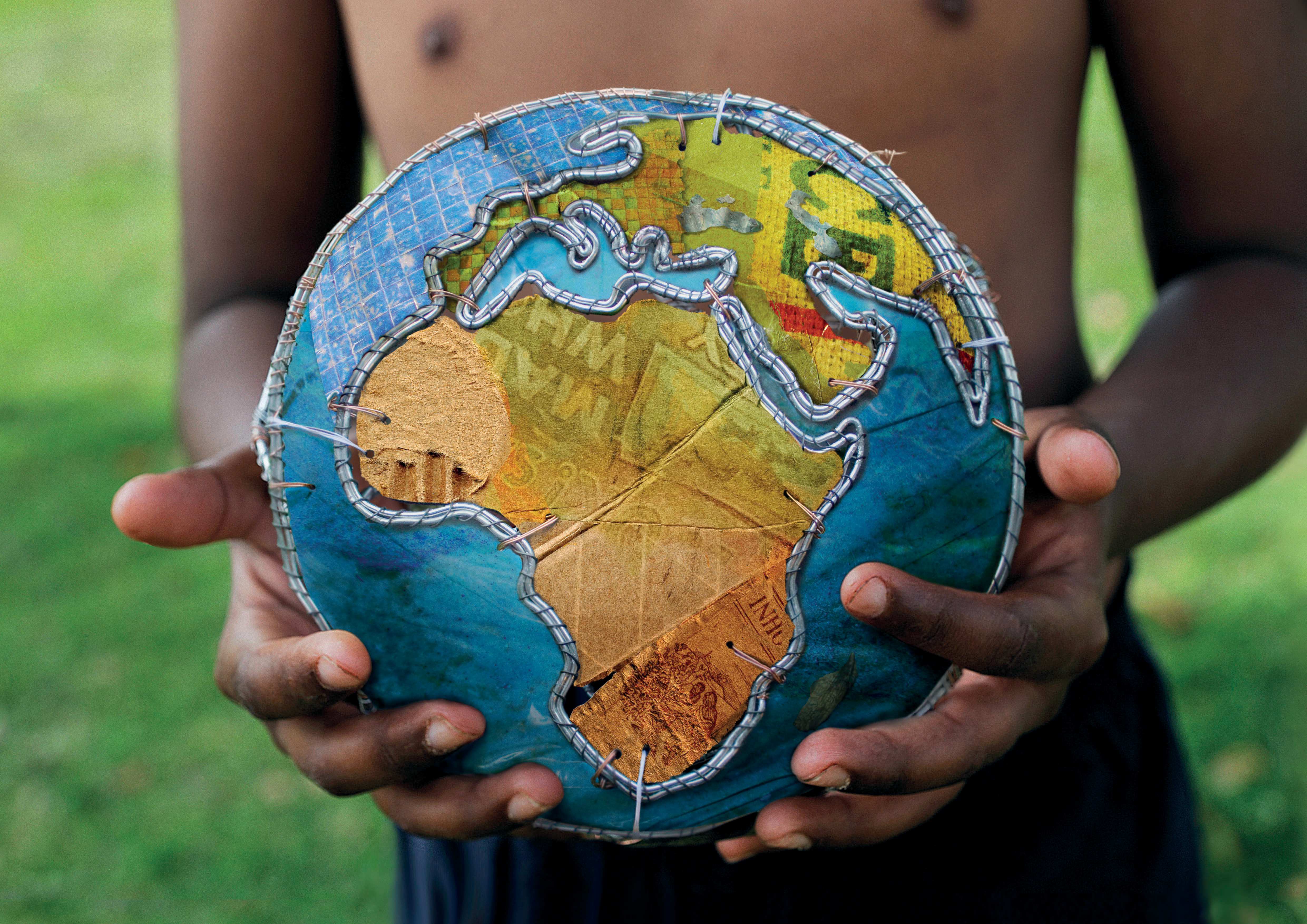 Ein Junge hält einen Ball, der wie ein Globus aussieht Ein Junge hält einen Ball, der wie ein Globus aussieht