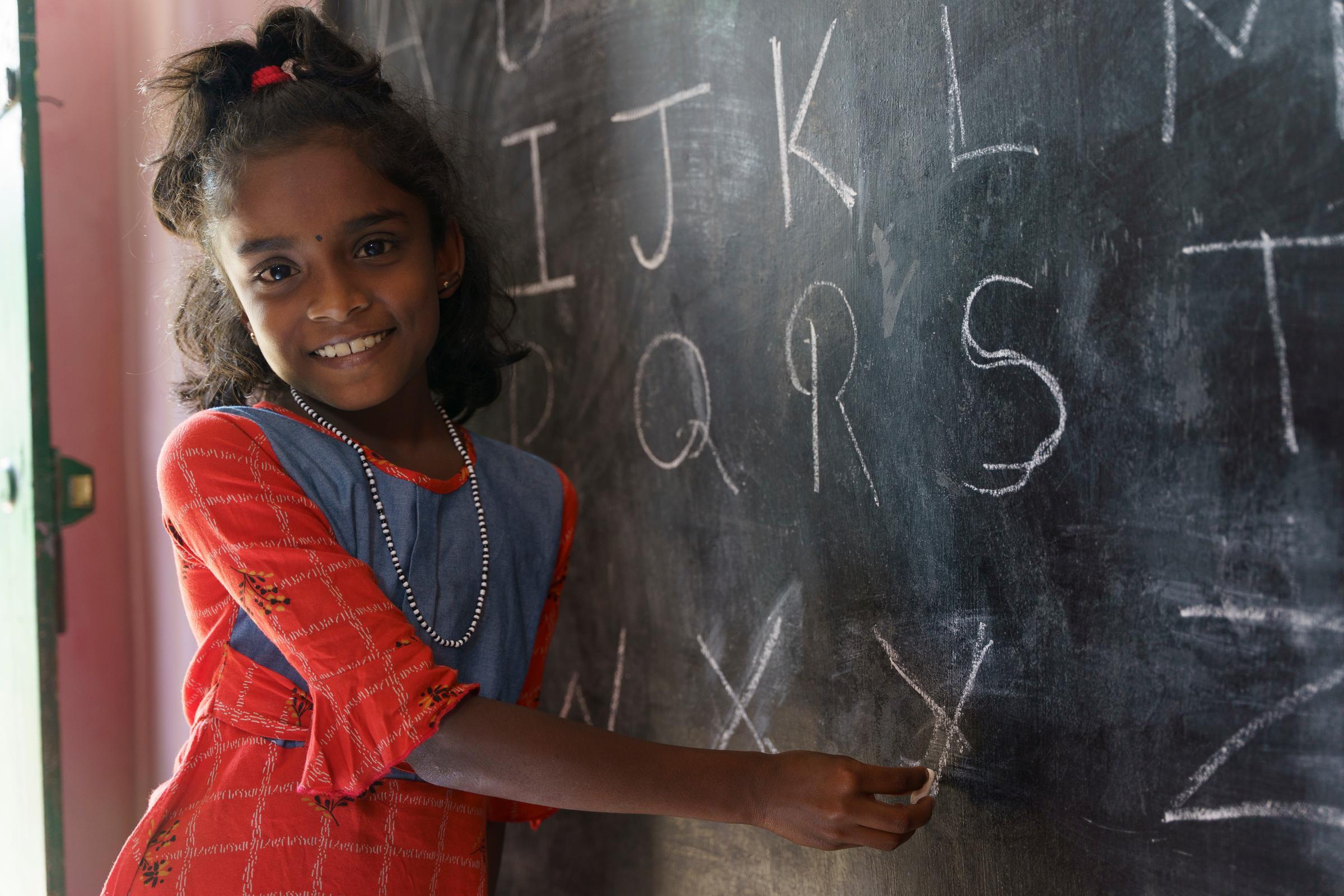 Ein Mädchen steht lachend an einer Tafel (Quelle: Christian Nusch) Ein Mädchen steht lachend an einer Tafel (Quelle: Christian Nusch)