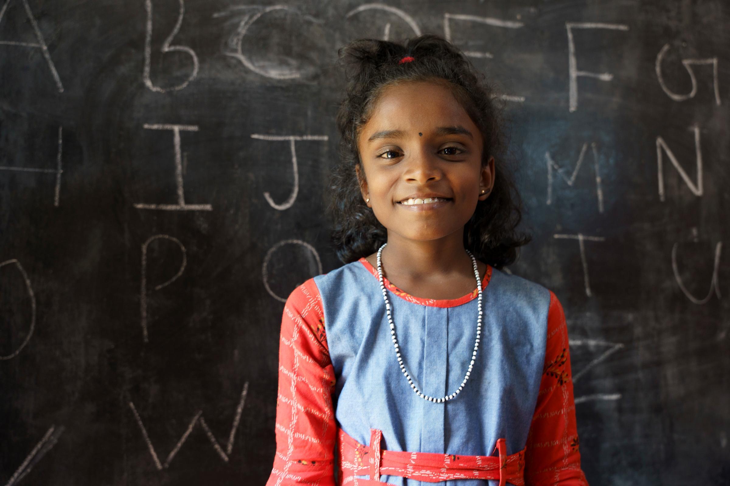 Ein sri lankisches Mädchen steht vor einer Schultafel Ein sri lankisches Mädchen steht vor einer Schultafel